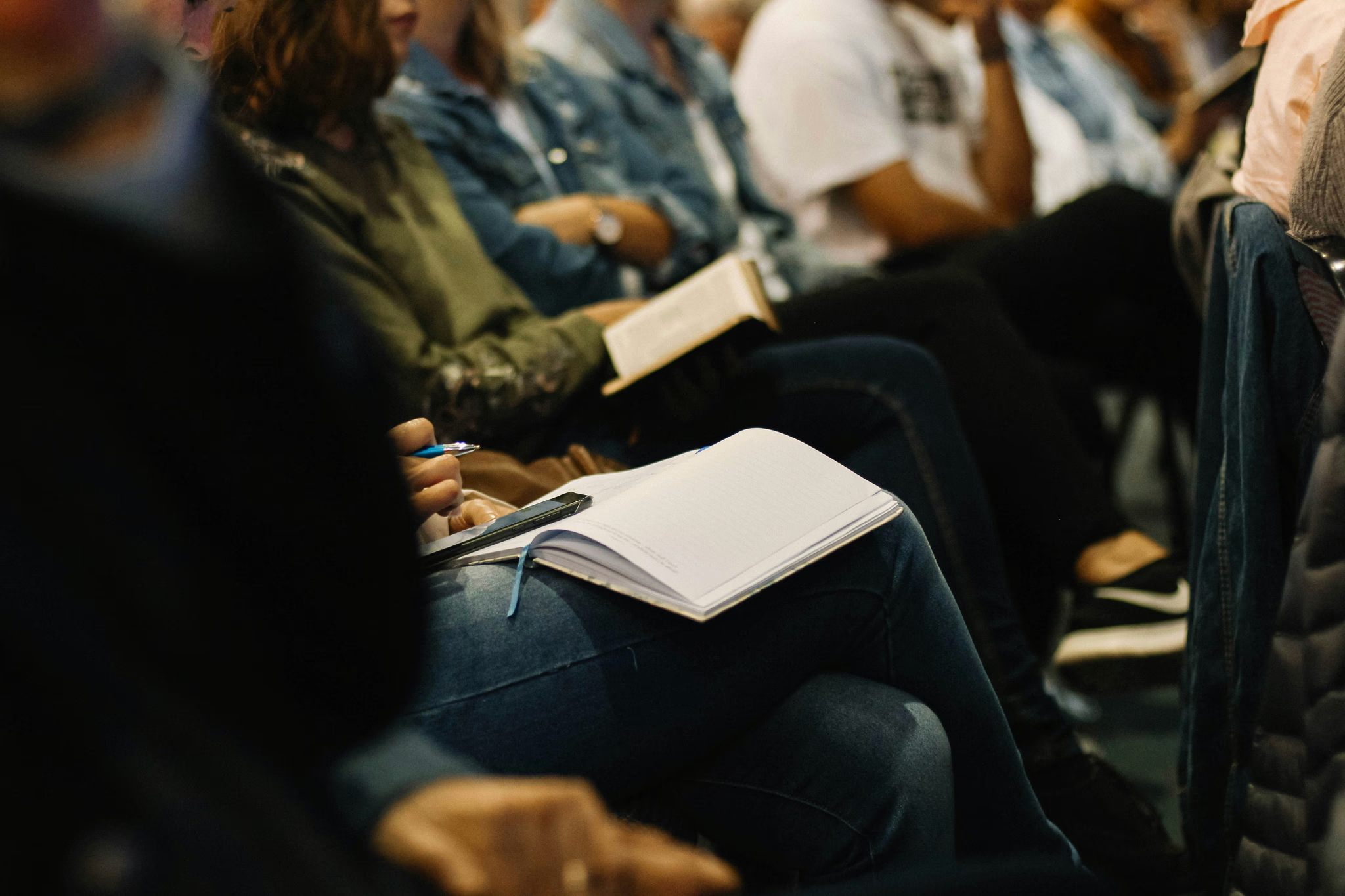 Students seated together taking notes and listening during a group session.