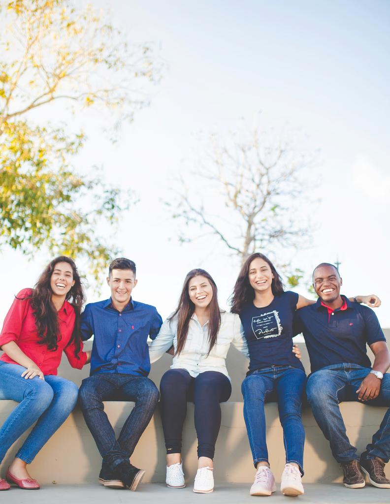 A smiling group of students sitting together outdoors.